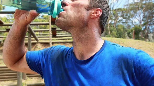 Fit man drinking water after workout during obstacle course