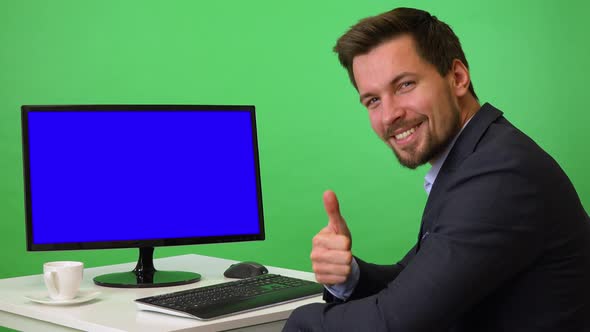 A Young Businessman Sits in Front of a Computer and Shows a Thumb Up To the Camera - Green Screen