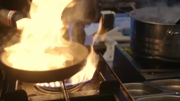 Male Chef Hands Cooking at Kitchen Restaurant. Fire Flame in Slow Motion.