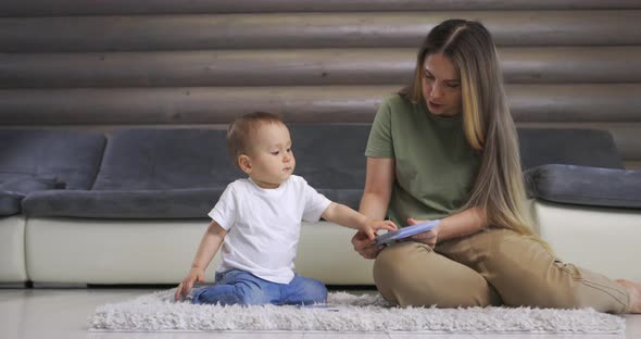 Happy Young Mother and Baby Son Playing with Alphabet Card on Warm Floor at Home Early Education at