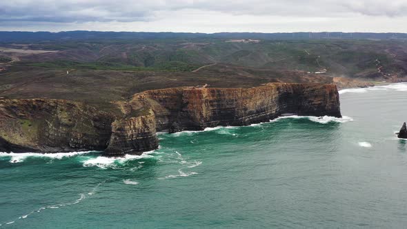Praia da Arrifana cliffs showing strata in west Portugal Atlantic coastline, Aerial circle shot