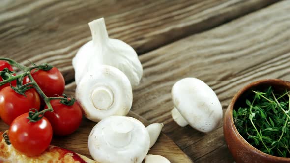 Italian pizza on wooden table with vegetables and spices