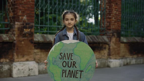 Little School Girl Demonstrating Banner with Inscription Massage Text Save the Planet Outdoor