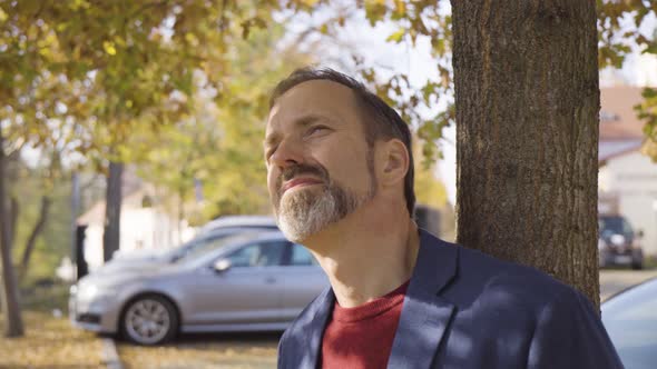 A Middleaged Handsome Caucasian Man Looks Around a Street in a Small Town in Fall  Closeup