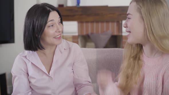 Portrait of Brunette Caucasian Woman Talking with Teen Blond Daughter at Home and Laughing. Positive