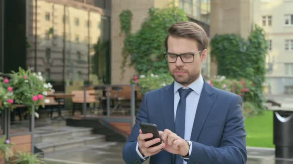 Businessman using Smartphone while Walking in Street in Slow Motion