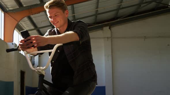 BMX rider using smartphone in an empty warehouse