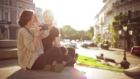 Young Beautiful Couple Taking Pictures Smiling Speaking Sitting in City Park