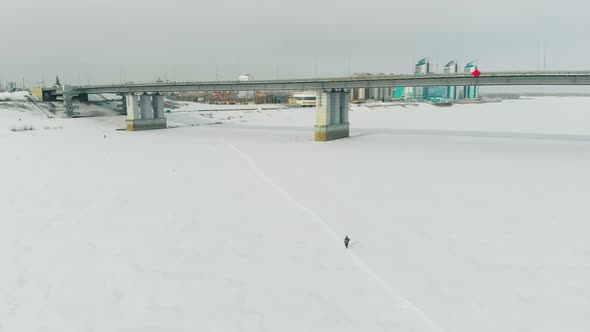 Person Silhouette Walks Along Snowy Path on Frozen River