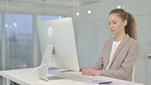 Serious Young Businesswoman Working on Desk Top in Office