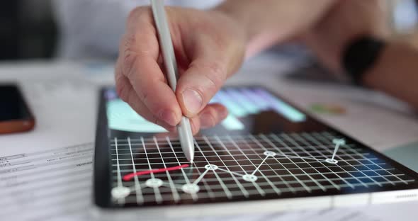 Marketer Draws Red Line on Business Graphs on Tablet