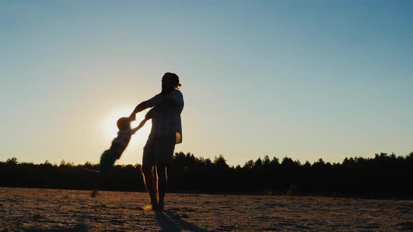 Healthy Father Playing with His Son at Sunset - Circling It. Beautiful Round Glare From the Sun in