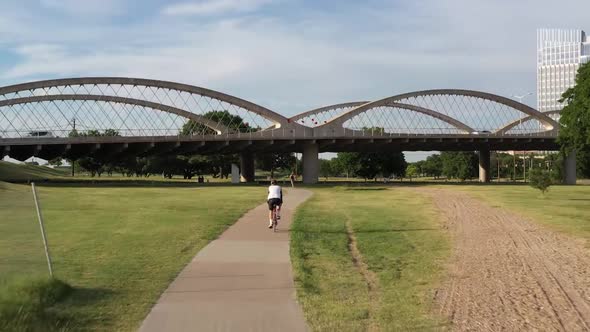 Drone video of Cyclist riding bike path near Trinity River Fort Worth Texas and 7th Street Bridge