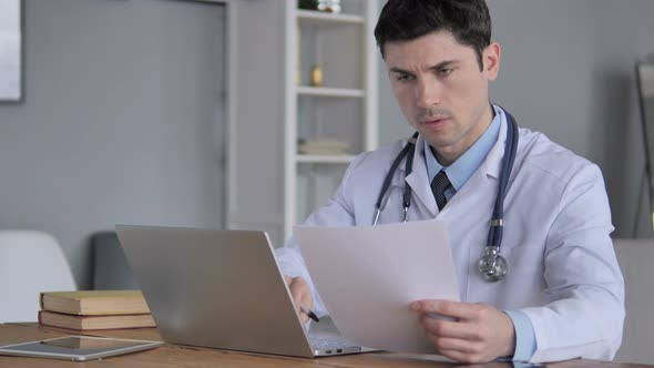 Doctor Working on Medical Report of Patient on Laptop
