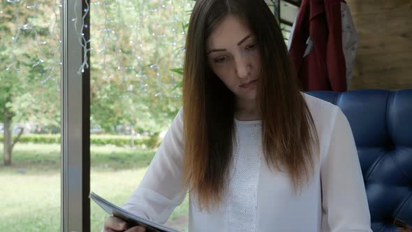 Young Woman in a Cafe Examining the Menu