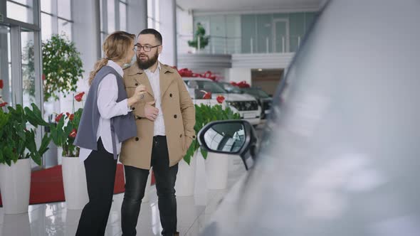 Husband and Wife Choose a New Car in the Showroom of an Official Dealer