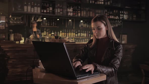 Attractive Business Woman Freelancer Working at Laptop and Smartphone While Sitting in Bar