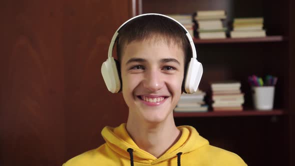 young student laughs and puts on white wireless headphones 