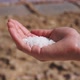 closeup of a hand holding salt in front of saltpans - VideoHive Item for Sale
