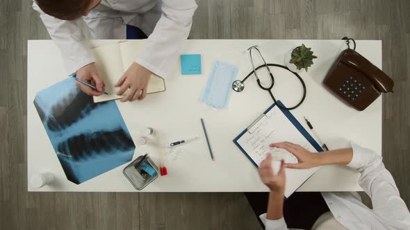 Doctors Working Together Writing Diseases in Medical Cards Top View