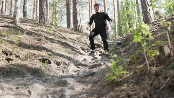 A young man is walking through trees A young man is coming down from the mountains