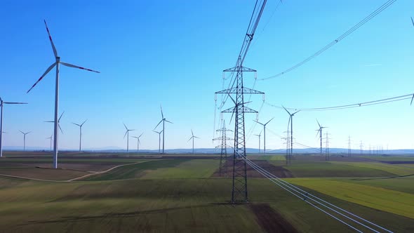 Scenic View Of Rotating Wind Turbines And Stream Mast Against Blue Sky In Green Fields. Aerial Drone