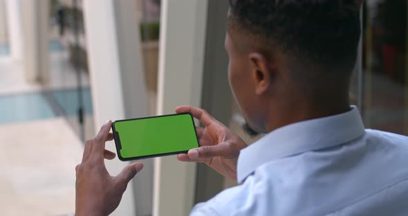 Overshoulder View of Afro American Guy Holding Phone in Horizontal Landscape Mode, Guy Looking and