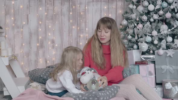 Mum Sits on Bed with Daughter and Entertains Little Girl