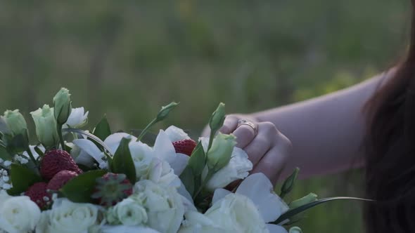 Woman's Hand Touches a Bouquet of White Roses and Strawberries Closeup