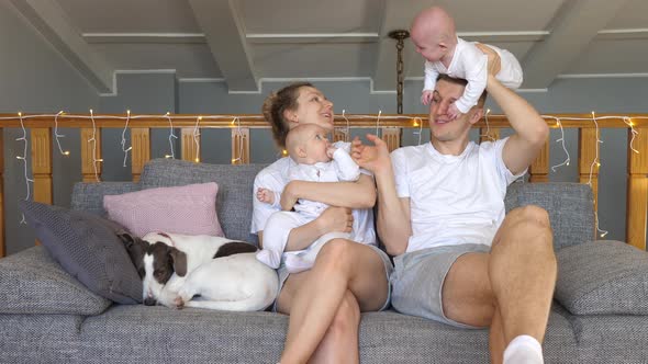 Young Happy Family Resting At Home With Twin Babies And Dog. 