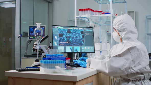 Scientist in Ppe Suit Typing Codes on Pc