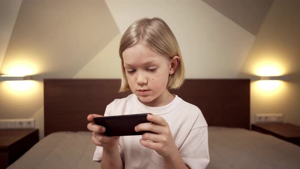 Blonde Boy Playing Games On The Phone