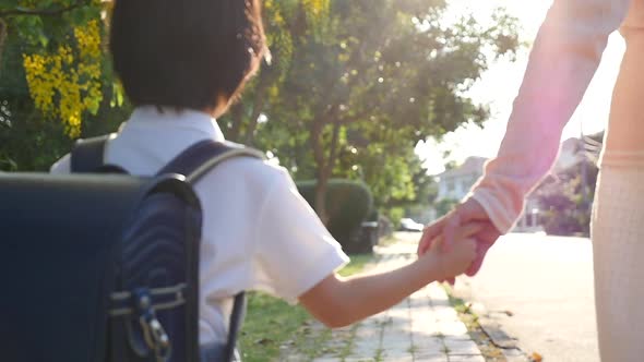 Asian Mother Holding Hand Of Little Son With Backpack Outdoors, Back To School