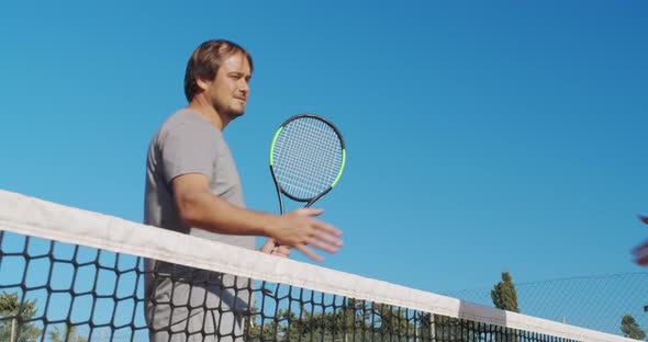 Players Handshaking After Tennis Match on Blue Sky Background