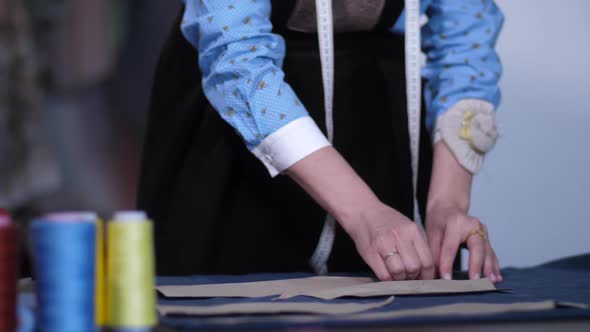 Hands of Tailor Working with Patterns on Fabric