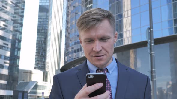 Businessman Using Smartphone while Walking to Office