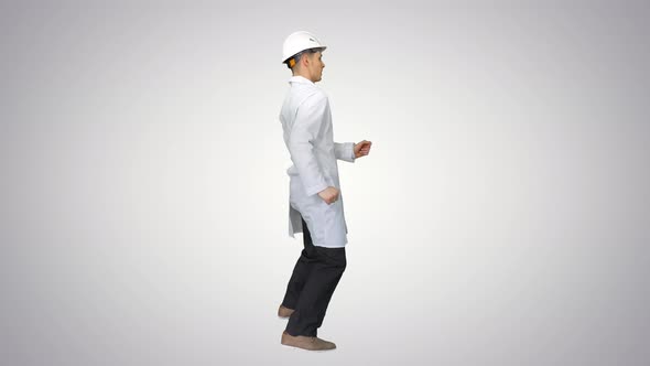 Young Workman with Helmet in White Robe Enjoy Dancing on Gradient Background.