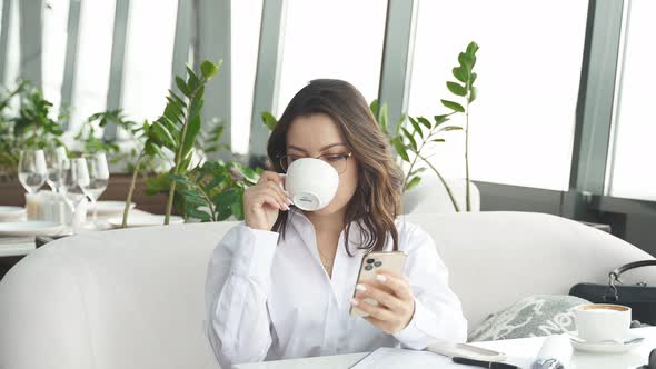 Happy Attractive Woman with Cute Smile Talking on Mobile Phone While Sitting Alone in Coffee Shop