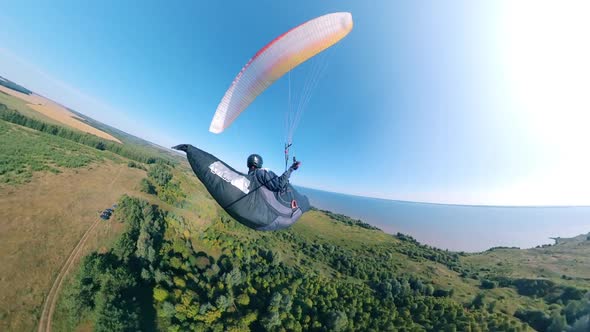 Green Land and a Person Flying Over It on the Paraplane