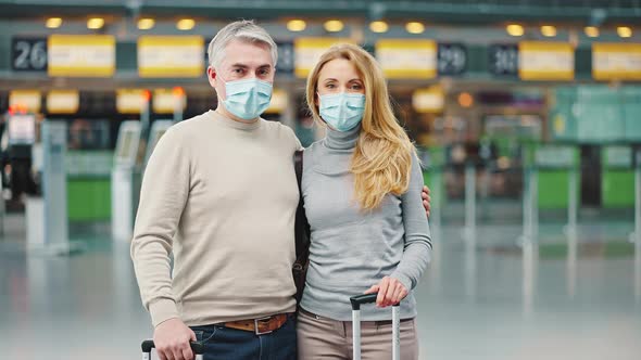 Portrait of Happy Middle Aged Couple Wearing Protective Face Masks Standing at Airport Building with