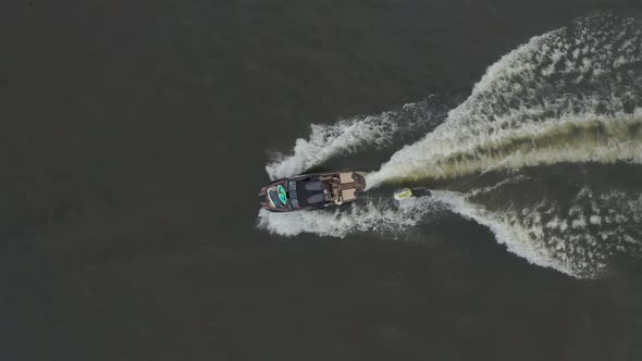 Aerial View of Woman Riding Wakeboard Behind Motorboat on Lake Water Sports Tracking Shot