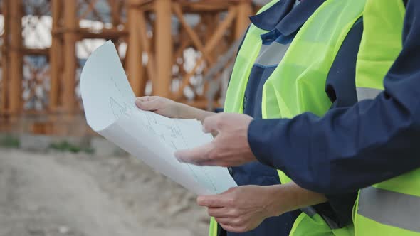 Unrecognizable Construction Workers Discussing Blueprint