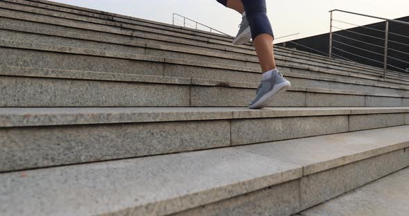 Fitness sportswoman running up stairs in city, slow motion