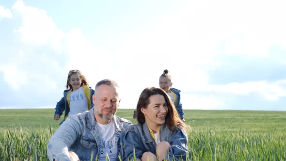 Cheerful Family Walks Through a Green Field of Wheat