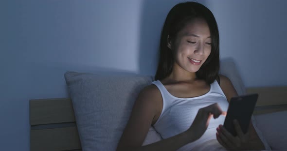 Young Woman using cellphone on bed