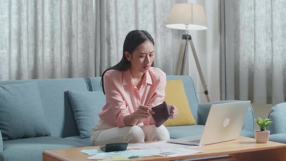 Asian Woman With A Laptop Looking At The Bill On Hand And Checking Money On The Purse