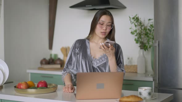 Front View of Focused Asian Young Woman Using Web Chat on Smartphone Talking Discussing Strategy