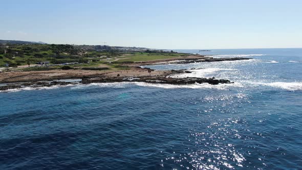 Drone Moving Along Sunny Coastline, View From the Sea. Aerial View of Cyprus Mediterranean Sea Shore