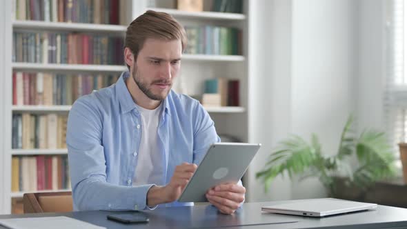 Man Reacting to Loss on Tablet While Sitting in Office