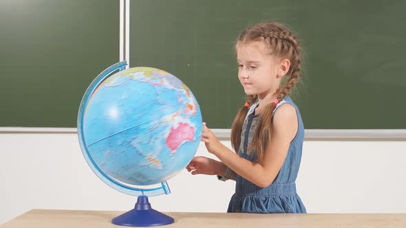 School Girl with Globe in Classroom Chalkboard on Background